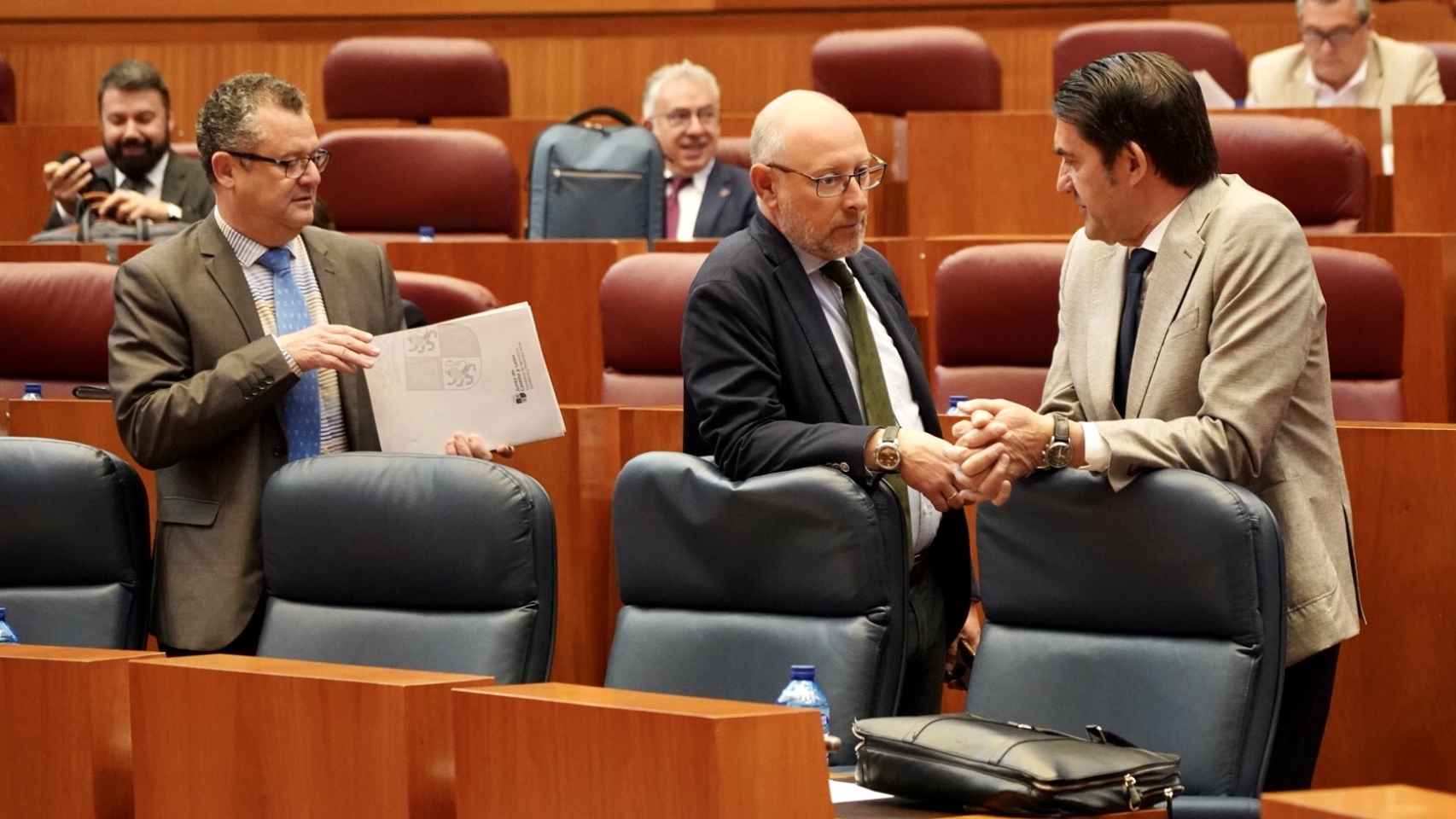 El consejero de Medio Ambiente, Juan Carlos Suárez-Quiñones, habla con el procurador de Vox Iñaki Sicilia, durante el pleno de las Cortes de este miércoles.