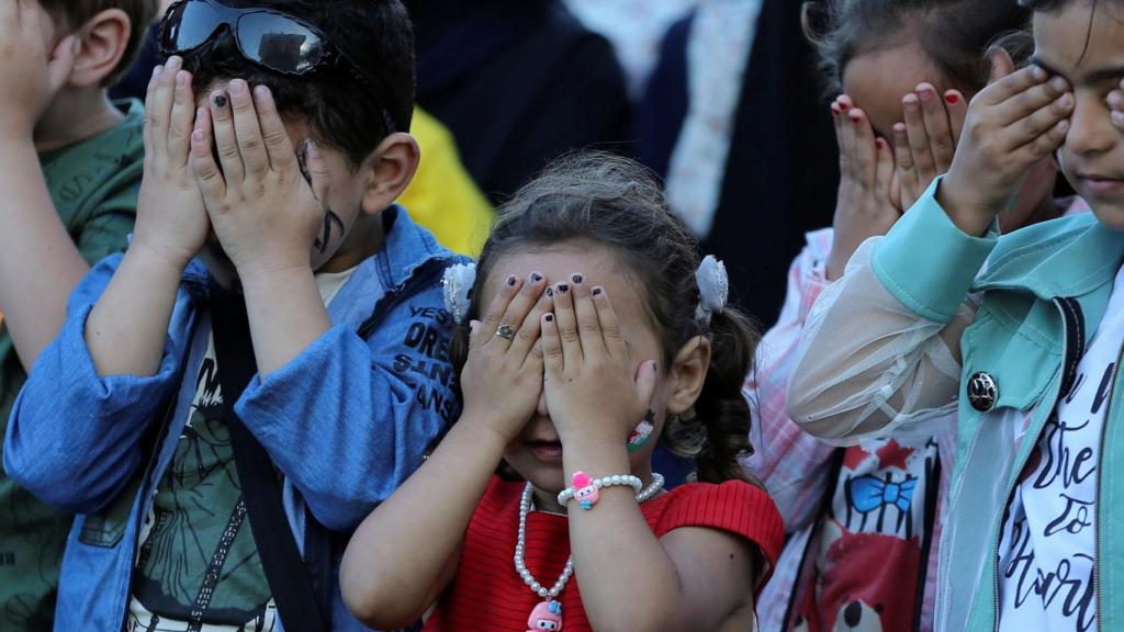 Unos niños se tapan los ojos jugando.