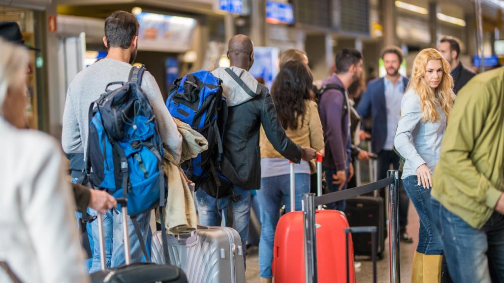 Decenas de viajeros esperan en un aeropuerto.