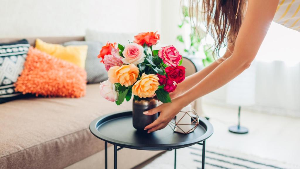 Las manos de una mujer que coloca flores en su salón.