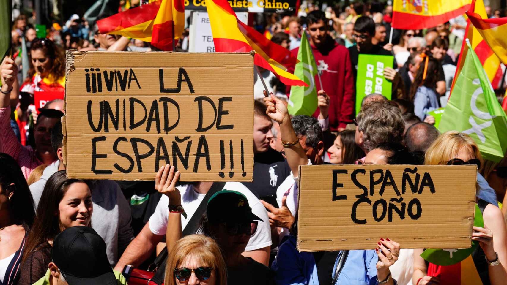 Dos manifestantes muestran sendas pancartas en el acto organizado por Vox este lunes en Madrid.