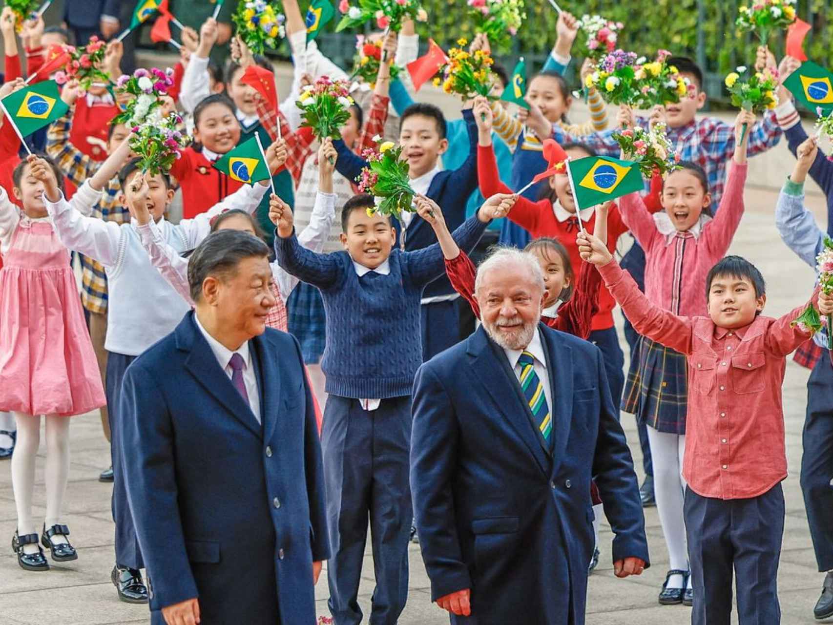 Un puñado de niños agita espontáneamente banderas del Brasil al paso de Xi y Lula.