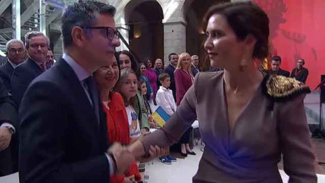 Félix Bolaños saluda a Isabel Díaz Ayuso, sujetándola por el brazo y con gesto desafiante,  este martes en la Puerta del Sol.