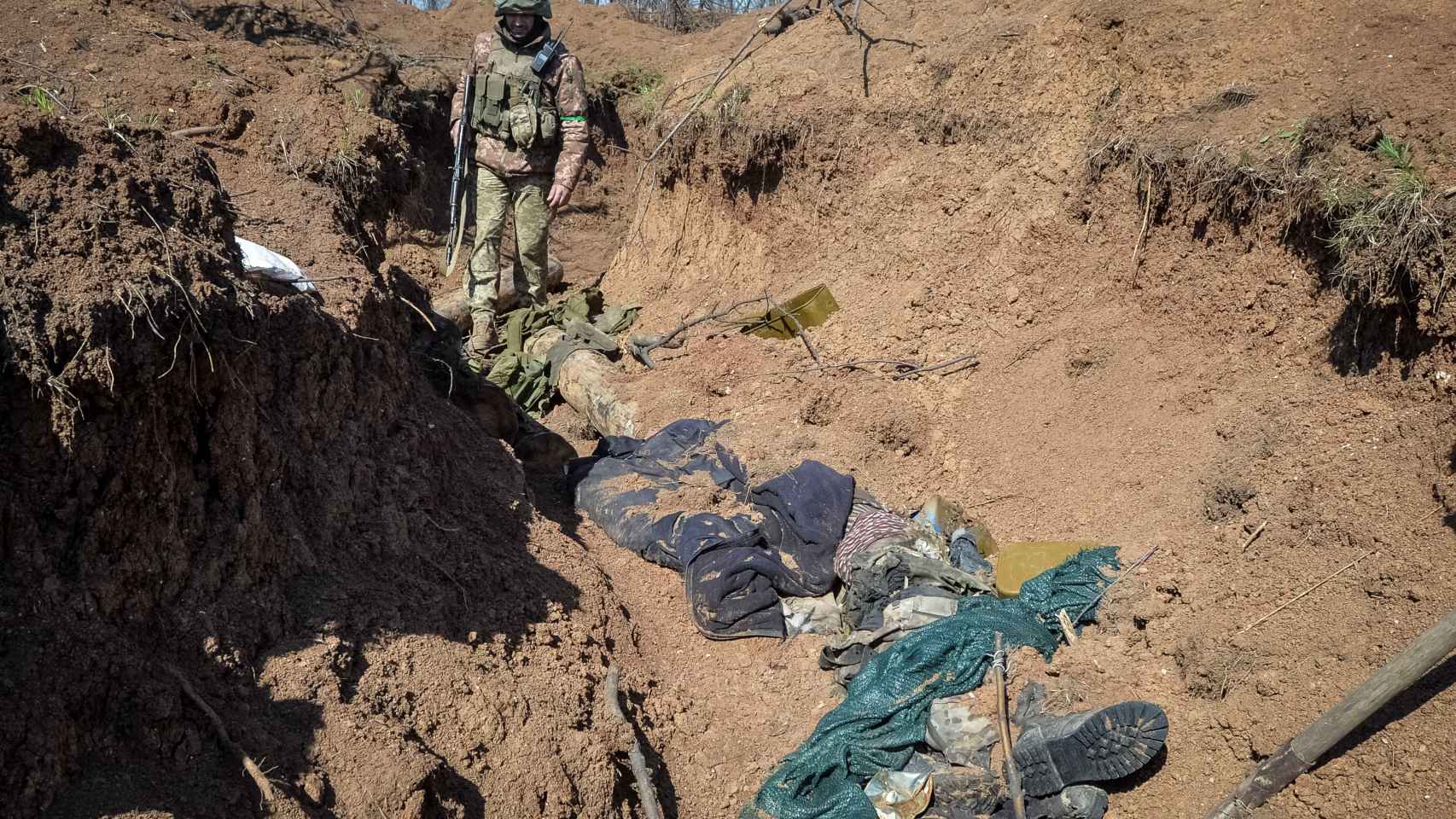 Un miembro del servicio militar ucraniano mira el cuerpo de un soldado ruso asesinado que yace en una trinchera en una posición en la línea del frente, mientras continúa el ataque de Rusia contra Ucrania, cerca de la ciudad de Bakhmut, Ucrania.