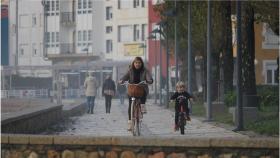 Una mujer pasea en bicicleta con su hijo en un pueblo de Galicia
