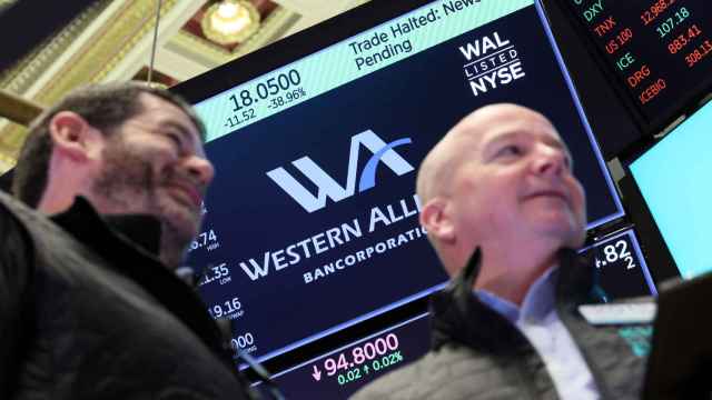 En una pantalla de la Bolsa de Nueva York se ve el logo de Western Alliance con varios agentes bursátiles por delante.