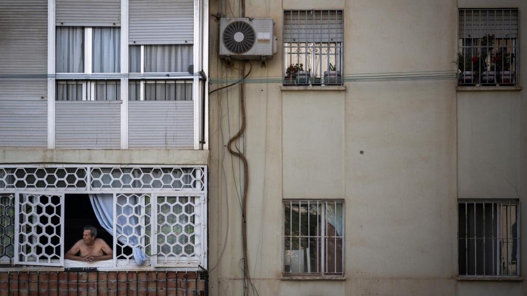 Un vecino se asoma a la ventana de su casa en La Palmilla.
