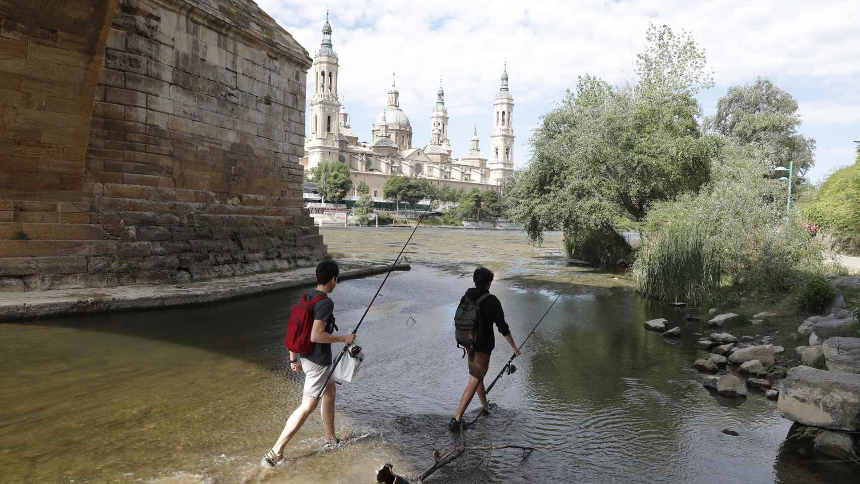 Dos viandantes cruzan el Ebro a su paso por Zaragoza.