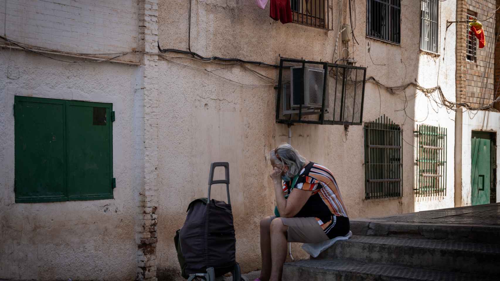 Una mujer sentada en una acera en La Palmilla, Málaga.