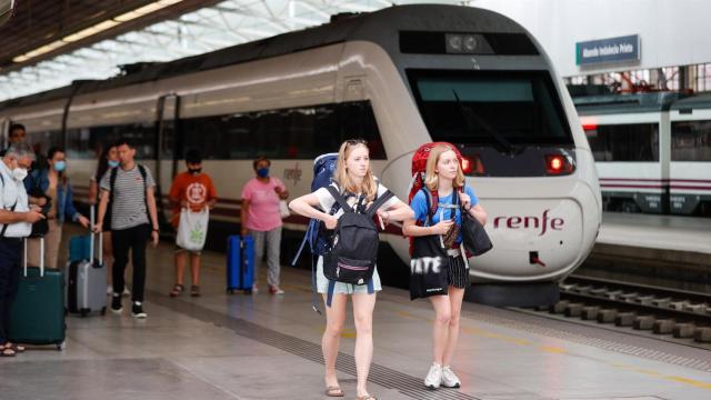 Dos jóvenes viajeras junto a un tren de RENFE.