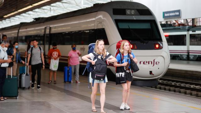 Dos jóvenes viajeras junto a un tren de RENFE.