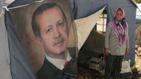 Ayse Kekec, una superviviente del terremoto que vive en una tienda de campaña, se para frente a un cartel de Erdogan.