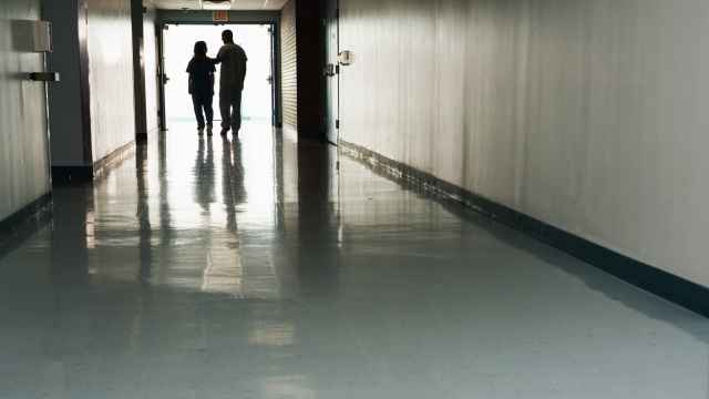 Dos personas caminan por un pasillo de hospital.
