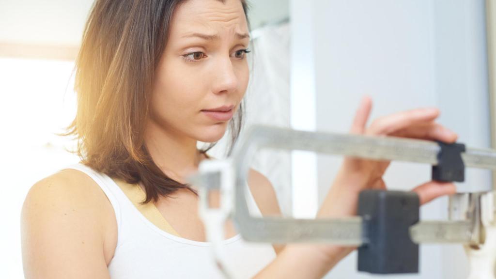 Mujer subida a una báscula. Foto: iStock.