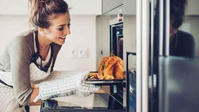Imagen de archivo de una mujer cocinando un pavo en el horno.