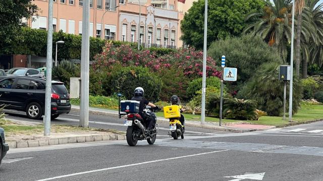 Un agente motorizado de la Policía Nacional acompaña a un cartero durante el reparto del voto por correo en Melilla.