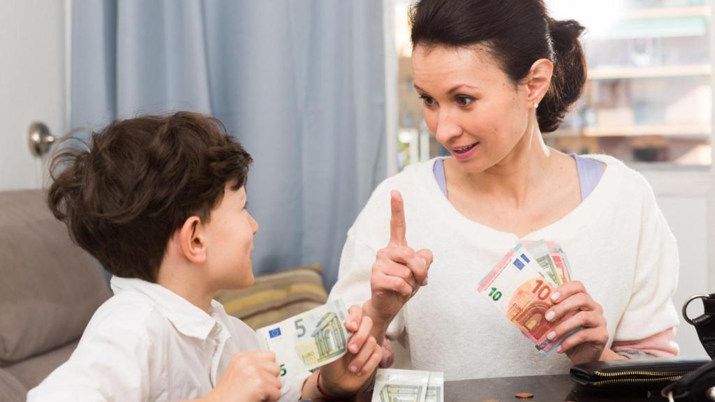 Un niño recibiendo la paga semanal de manos de su madre.