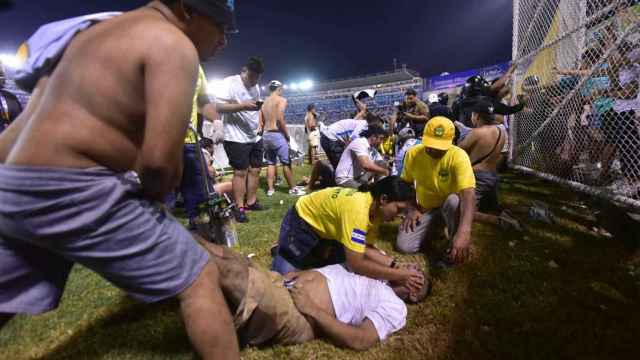 Aficionados auxilian a otros después de una estampida en un estadio de fútbol de El Salvador