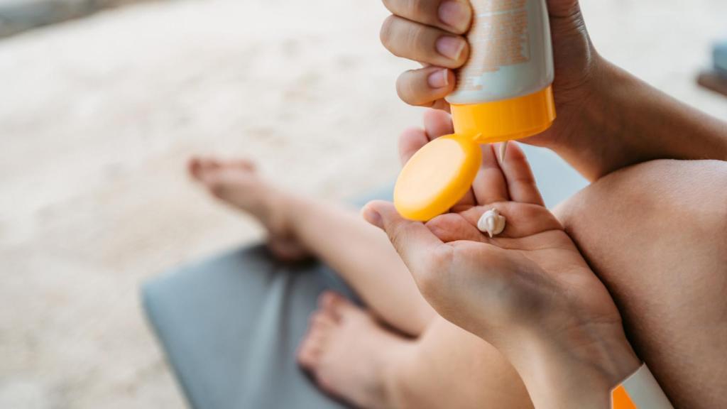 Mujer aplicando crema solar en la playa. Foto: iStock.