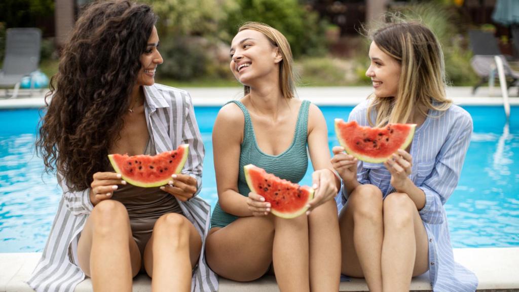 Tres amigas comiendo sandía en la piscina. Foto: iStock.