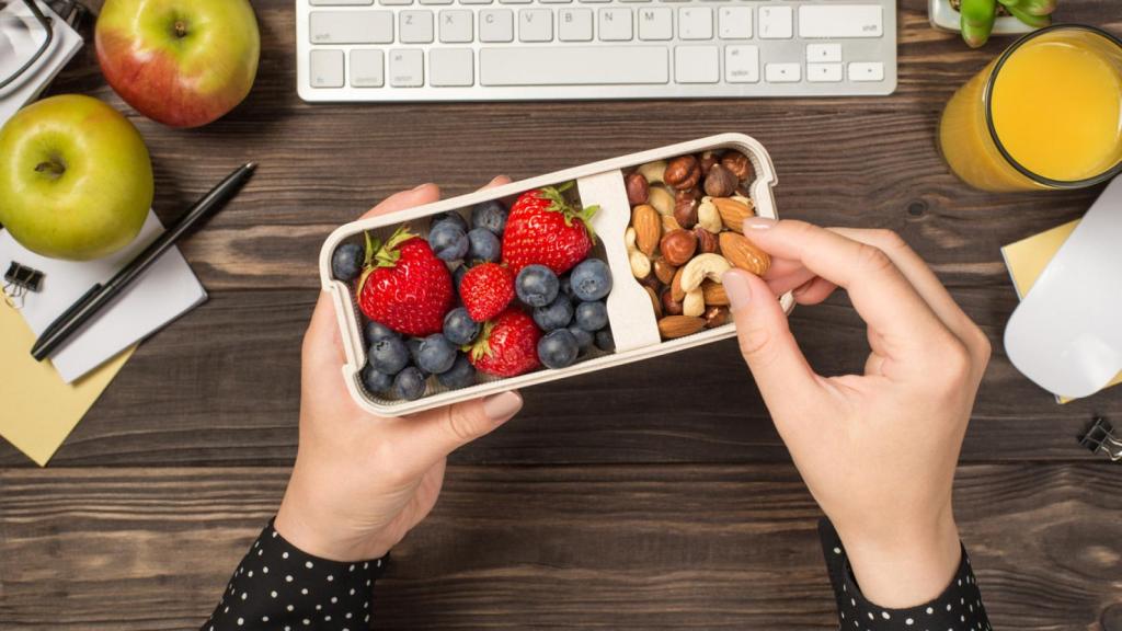 Mujer tomando frutos secos y fruta a media mañana. Foto: iStock.