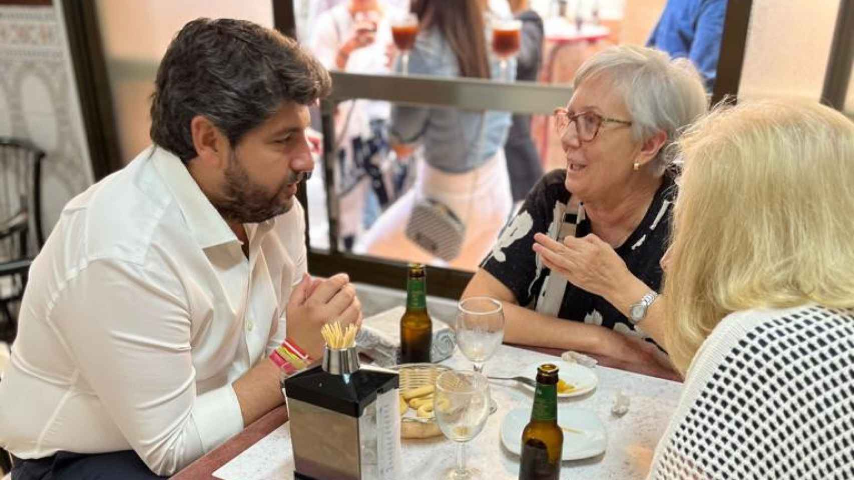 López Miras, este viernes, charlando con dos clientas de la taberna Luis de Rosario en Murcia.