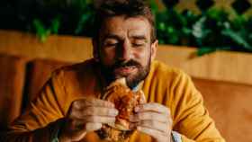 Un hombre comiéndose una hamburguesa.