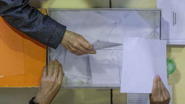 Una persona deposita un voto en una urna.