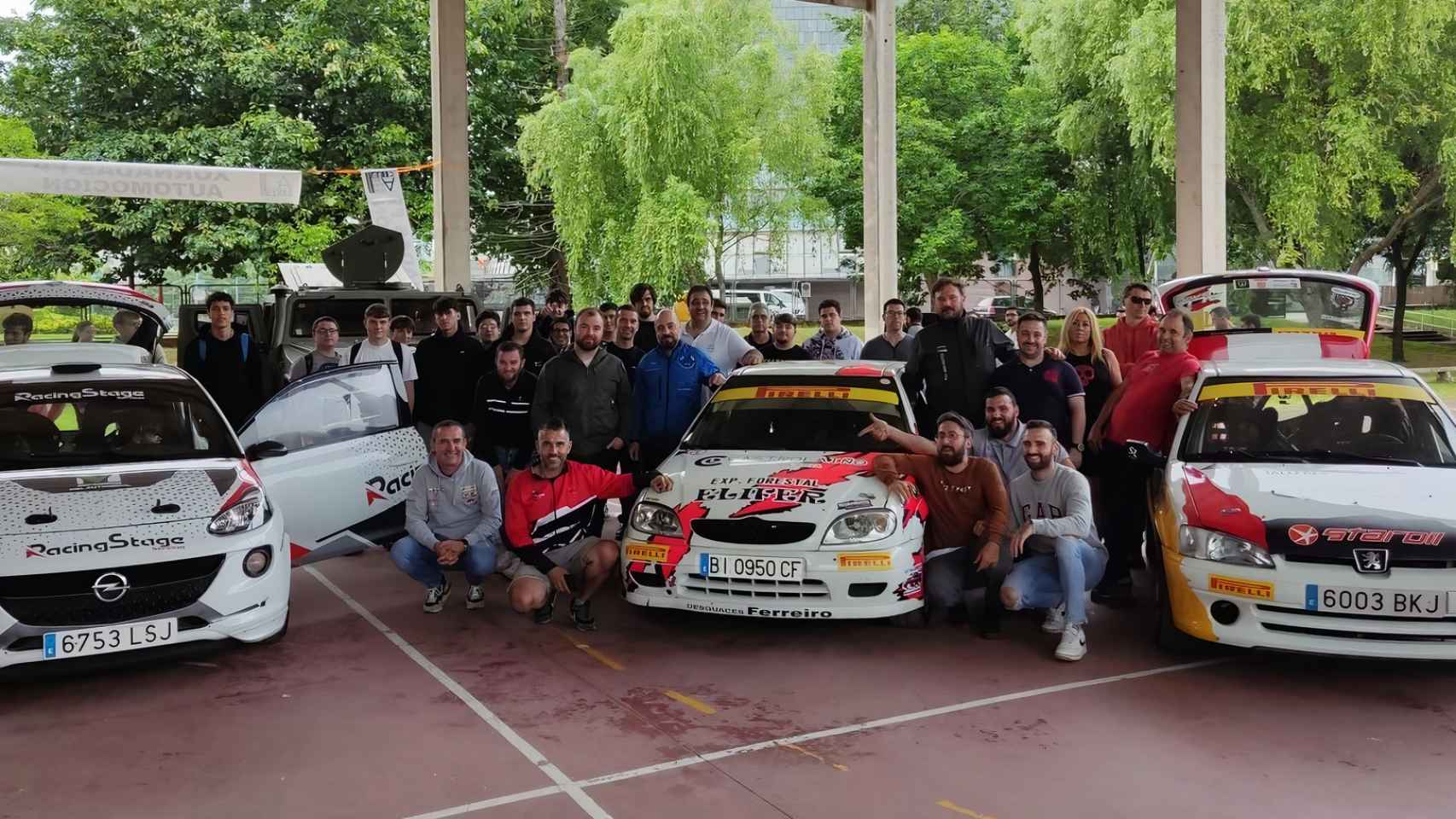 El grupo de estudiantes posa junto a los coches y con los pilotos que estuvieron presentes en la charla.