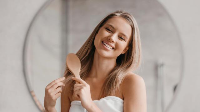 Una mujer, cepillando su pelo.