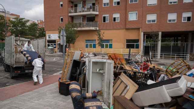 Dos trabajadores cargan en un camión las pertenencias de las familias desalojadas en Alcobendas este viernes.