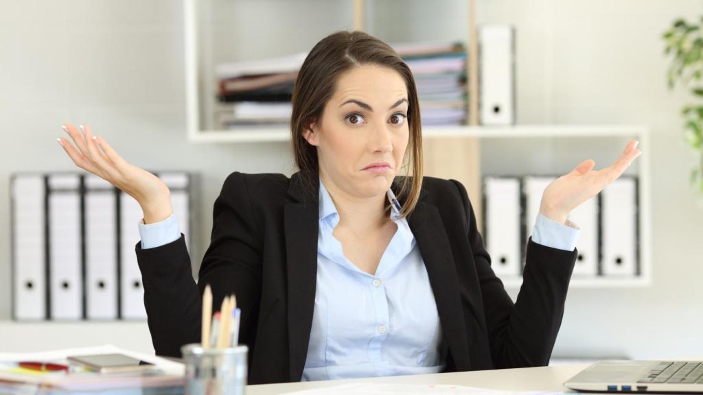 Una mujer en su puesto d etrabajo con cara de confundida.