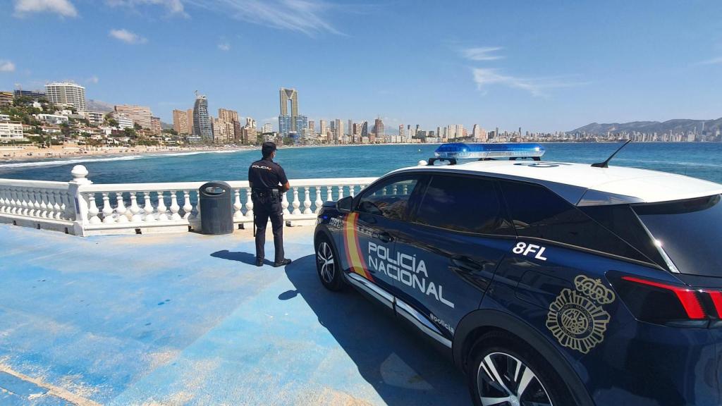 Un agente y un coche de la Policía Nacional observan Benidorm desde la playa de Poniente, en imagen de archivo.