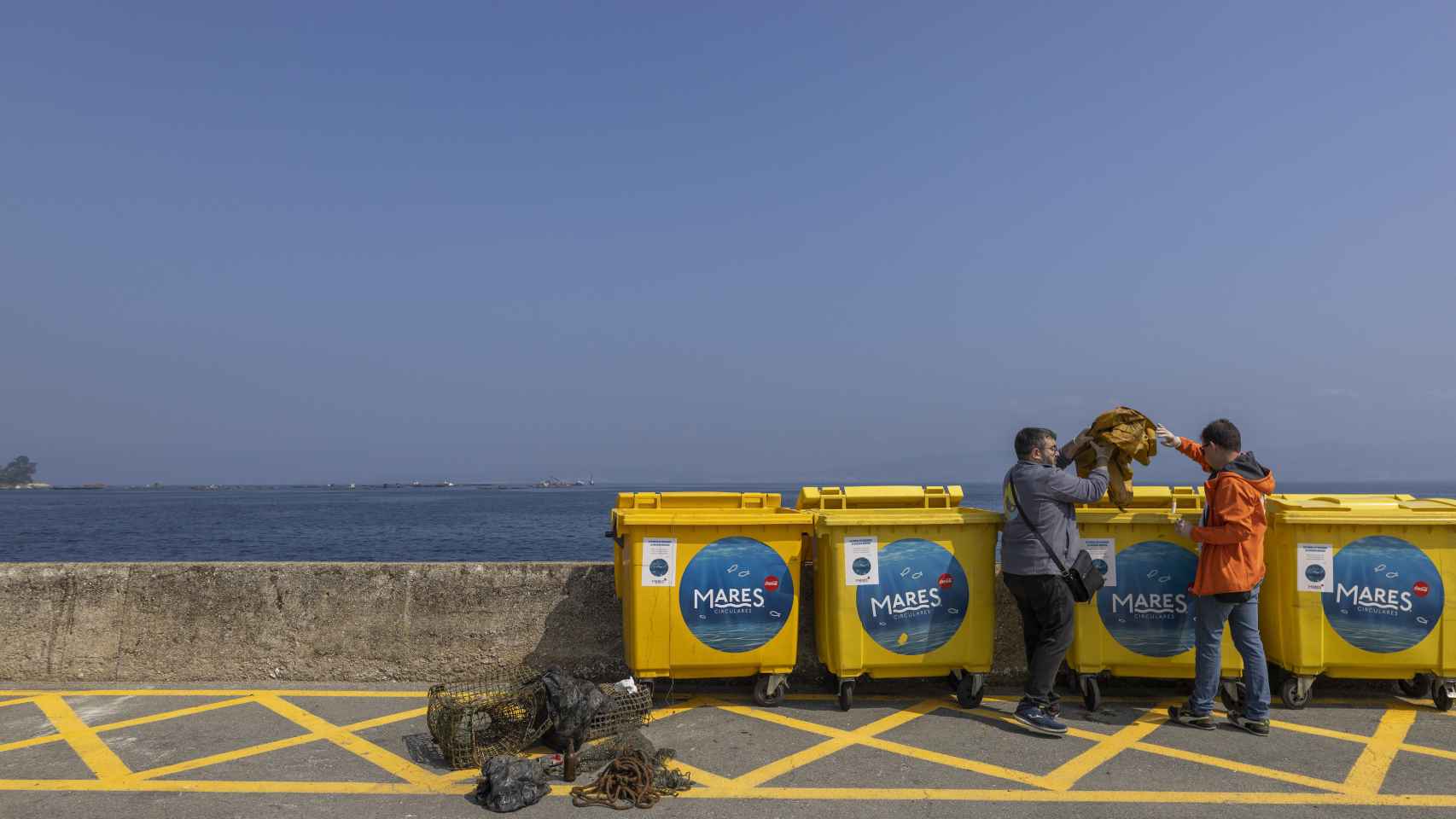 Juan Pablo Pérez y Rubén Rodríguez, técnicos de Vertidos Cero, depositan una red con residuos en los contenedores de Mares Circulares colocados en el puerto de Breu.