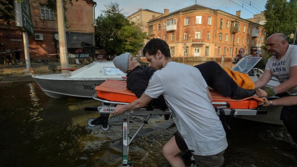 Los voluntarios evacuan a un residente local de un área inundada después de que se rompiera la represa de Nova Kajovka, en Kherson.