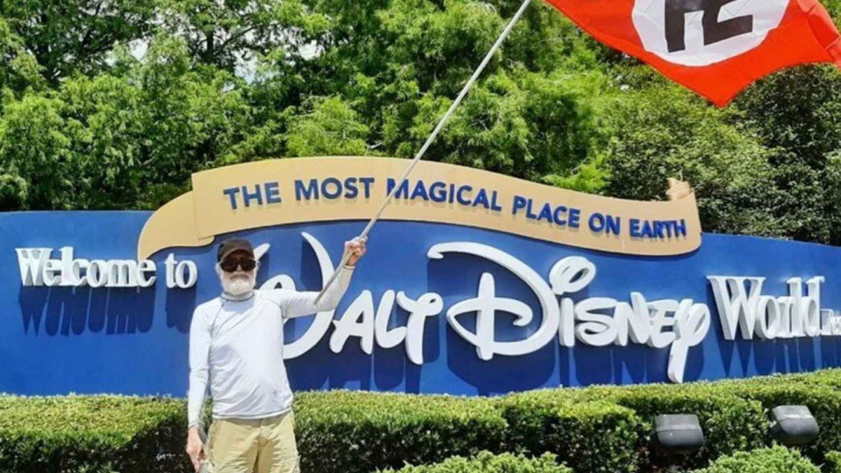 Un hombre ondea una bandera nazi delante de la entrada a Disney World Florida, este sábado.
