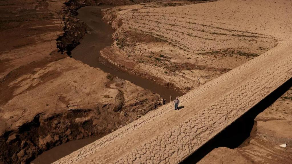 Un hombre camina sobre el embalse seco de Baells, en Cataluña.