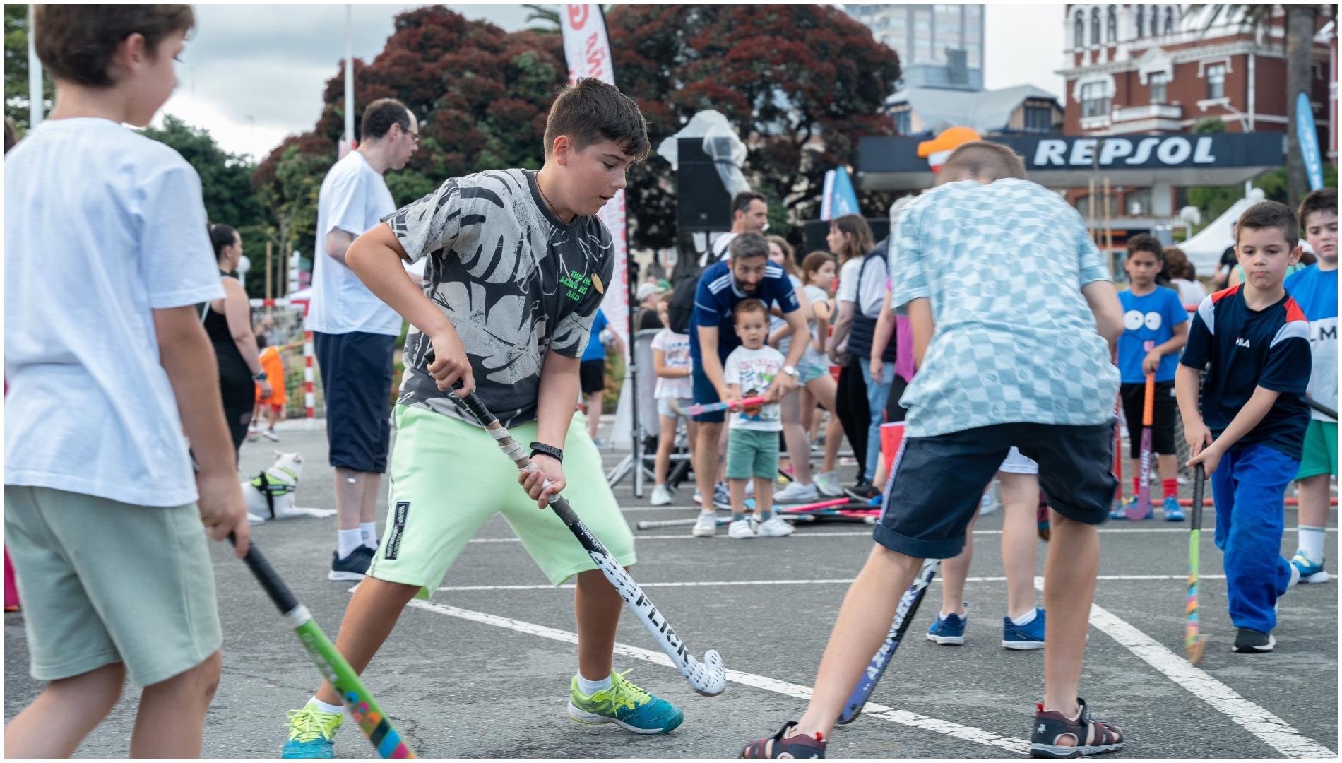 Varios niños practican hockey en el Día do Deporte na Rúa