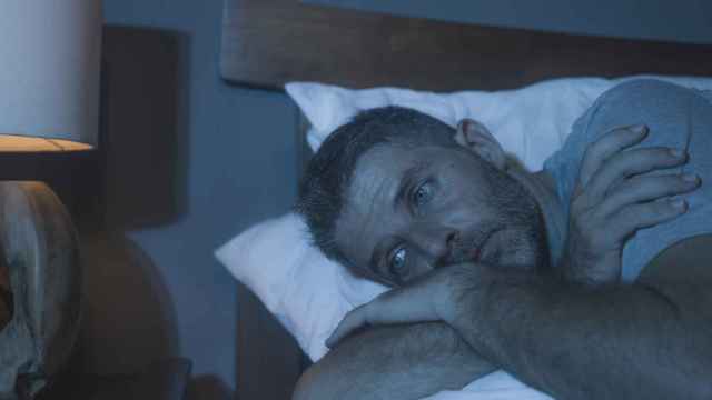 Imagen de un hombre en la cama mirando al vacío por culpa del insomnio.