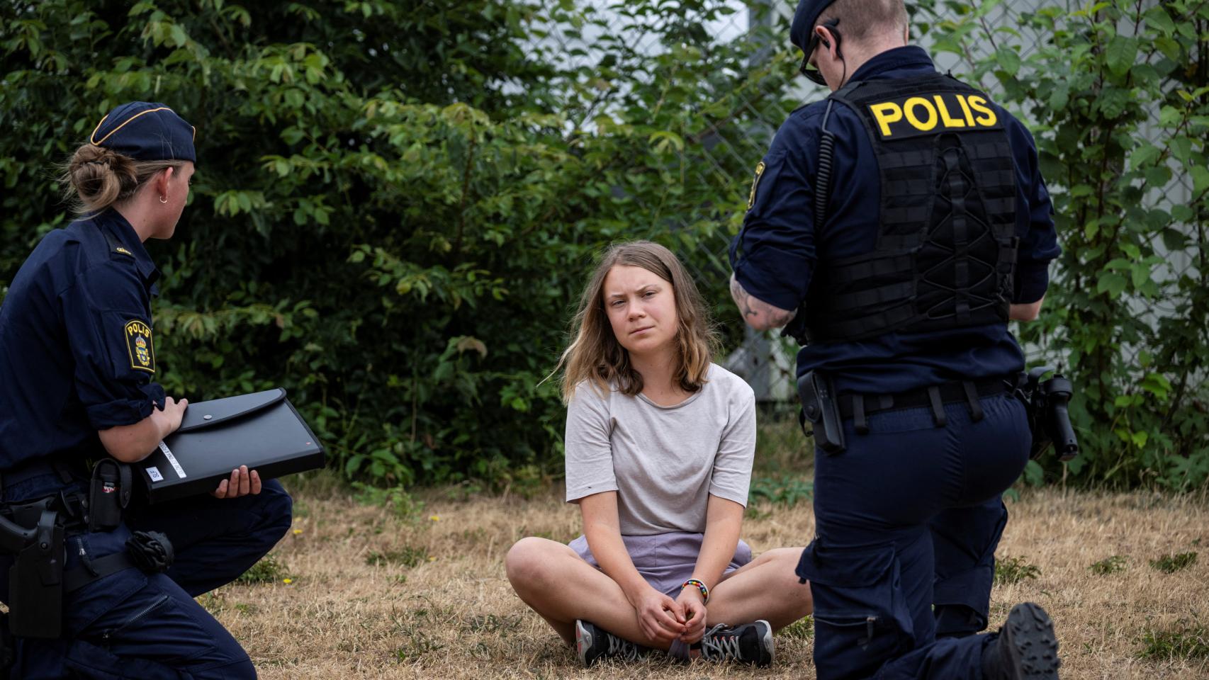 Dos agentes de la Policía sueca hablan con Greta Thunberg.