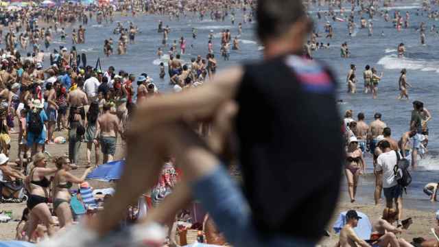 Una persona observa una playa valenciana llena de gente, la semana pasada.