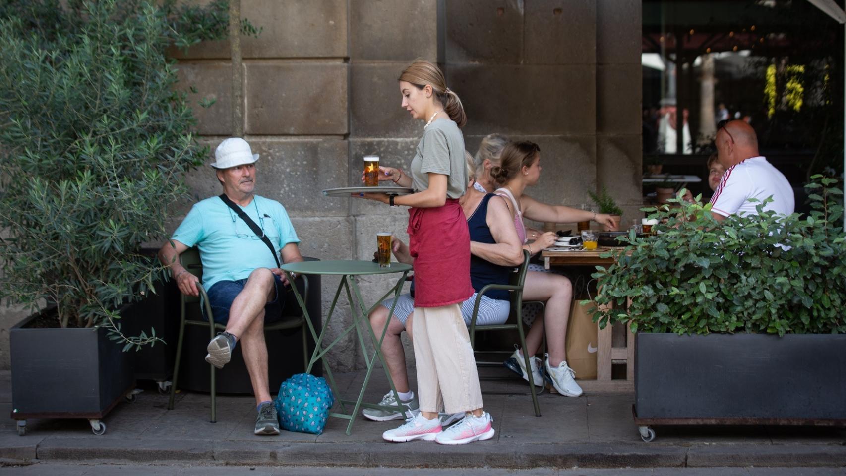 Una camarera sostiene una bandeja en la Plaza Real de Barcelona.