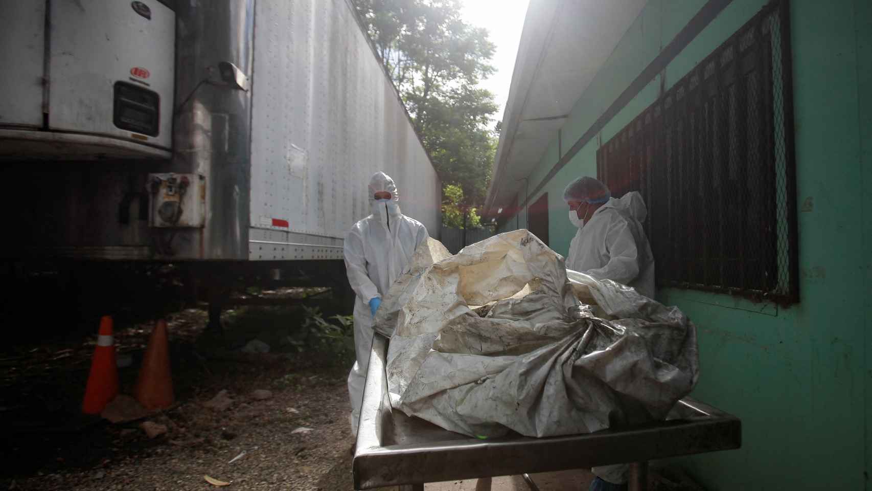 Técnicos forenses descargan un cadáver de un remolque frigorífico en la morgue de Tegucigalpa, este miércoles.