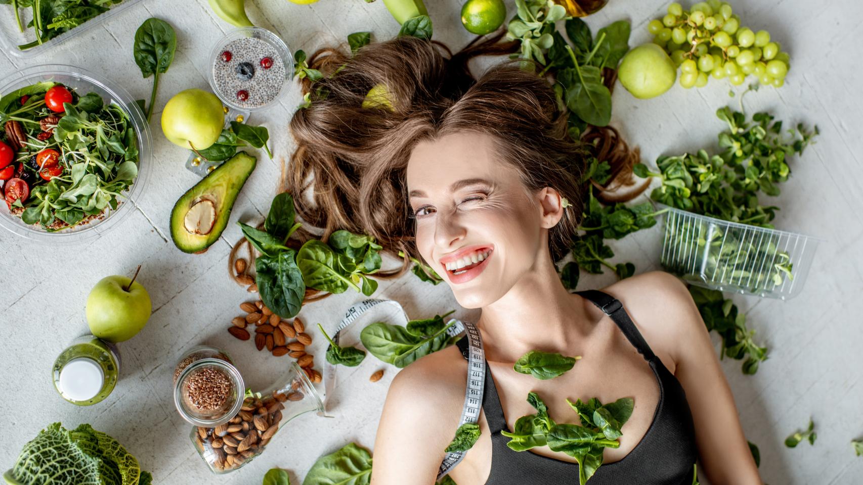 Mujer que giña el ojo rodeada de comida saludable. Foto: iStock.