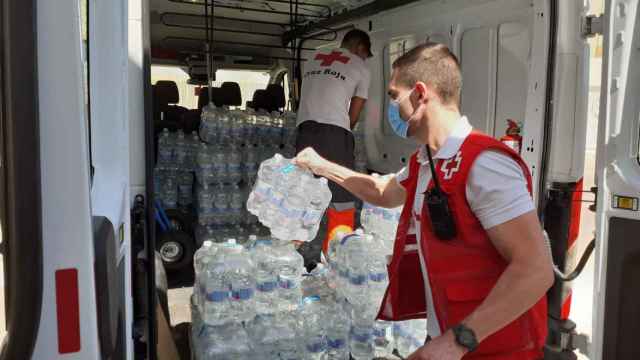 Voluntarios de Cruz Roja cargan botellas de agua en una furgoneta para su posterior reparto. CRUZ ROJA