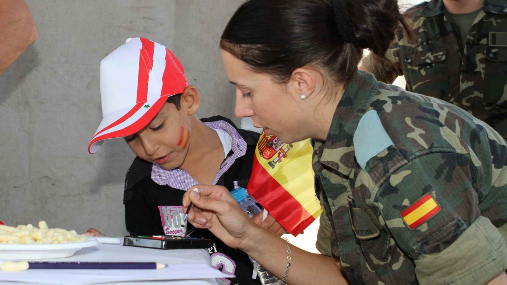 Una militar española junto a un niño.