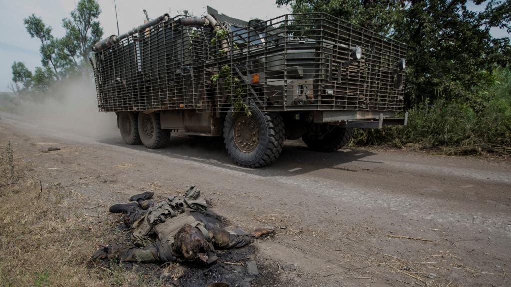 Un vehículo ucraniano pasa ante el cadáver de un soldado ruso en Donetsk