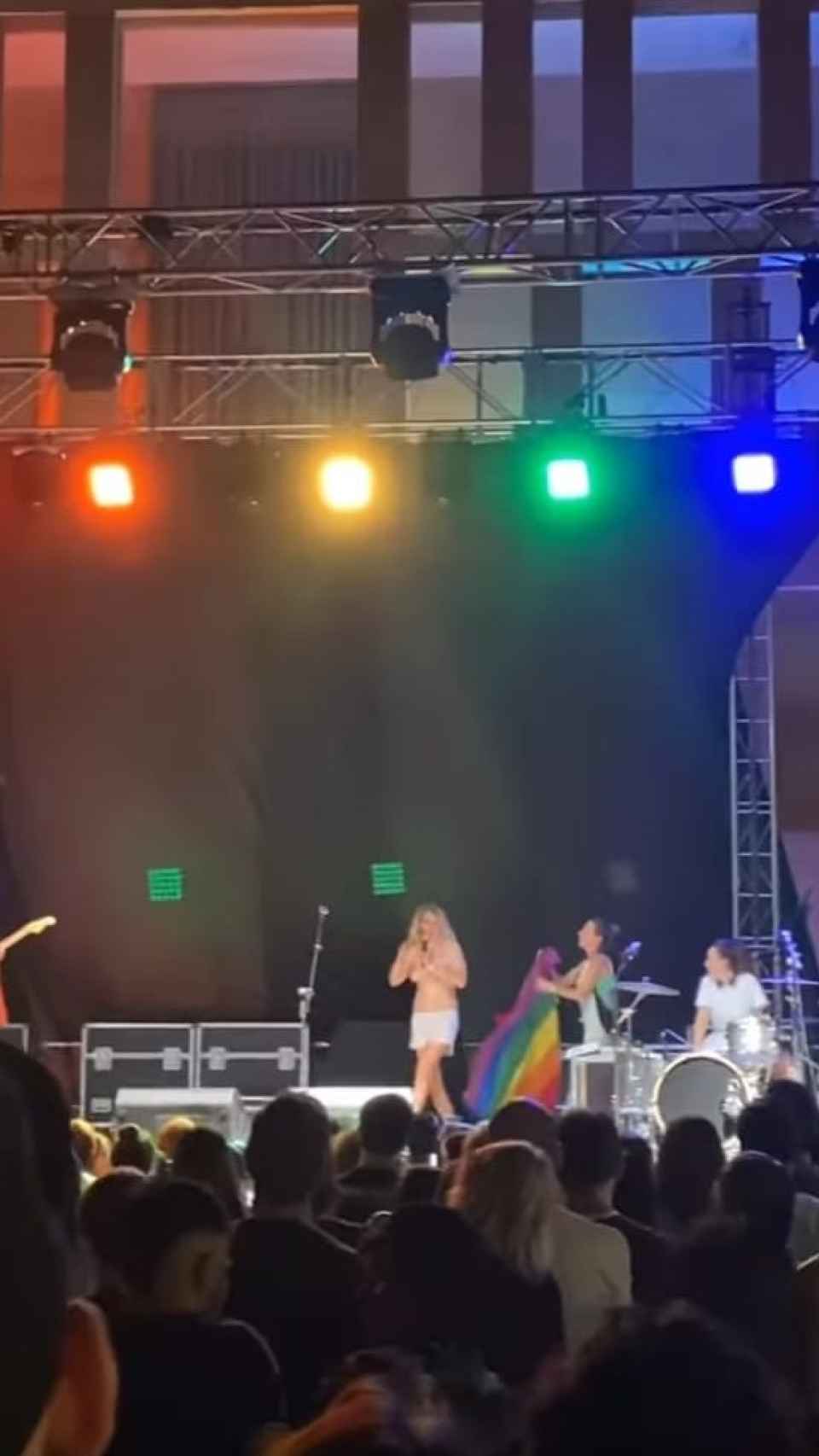 Una persona de la organización del concierto sale con una bandera arco íris para tapar los pechos de Rocía Saiz.