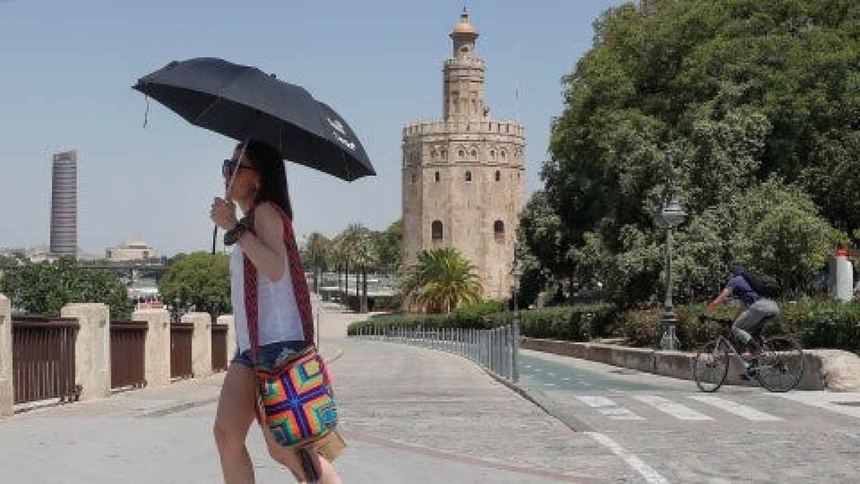 Una chica se refugia del calor bajo su paraguas en Sevilla.
