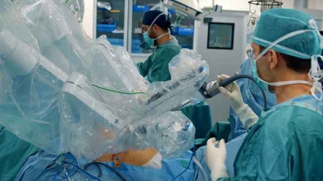 Equipo de sanitarios que realizando una intervención quirúrgica junto con un robot médico